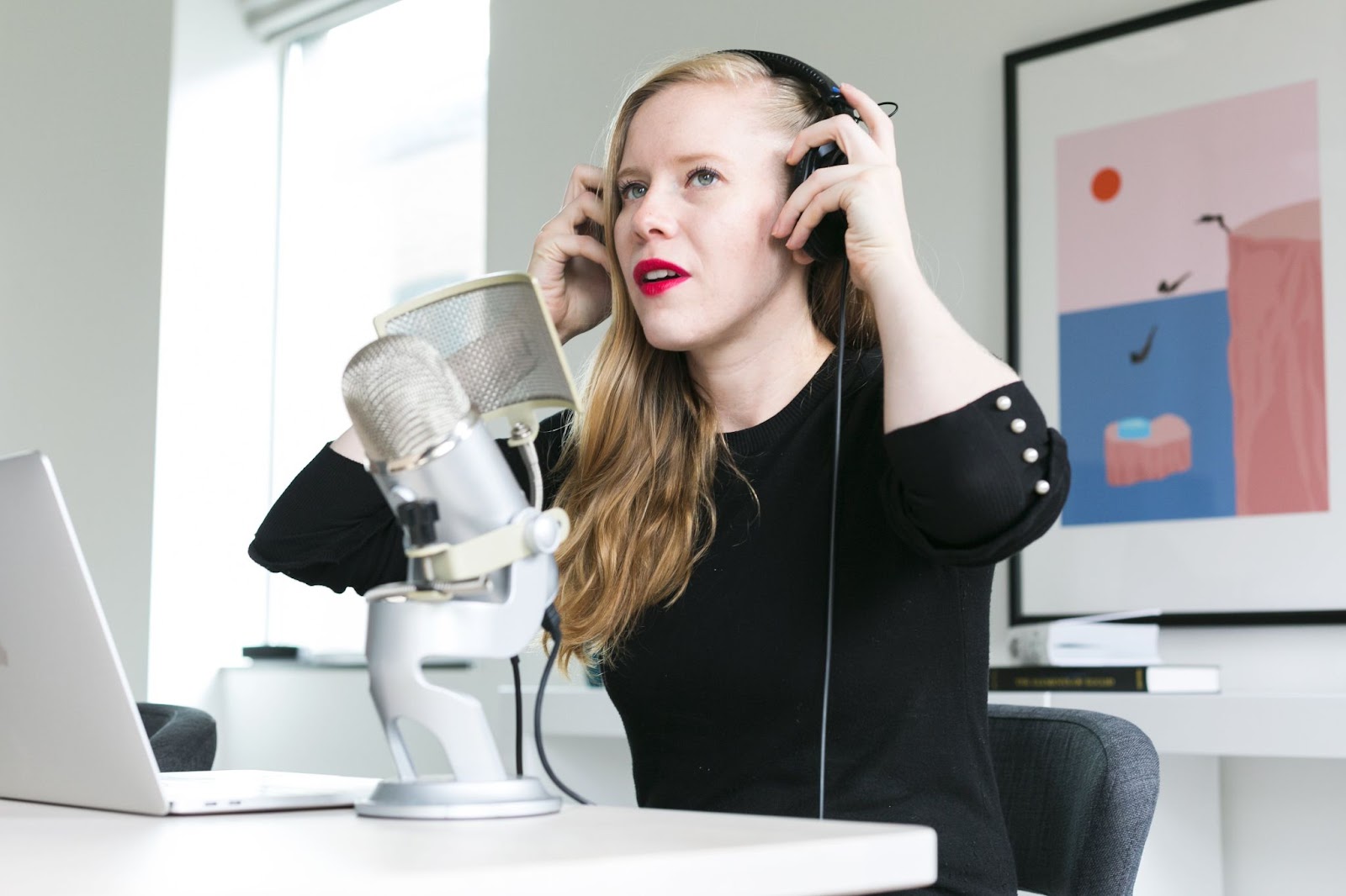 Woman adjusting her headphones before recording herself on the microphone.